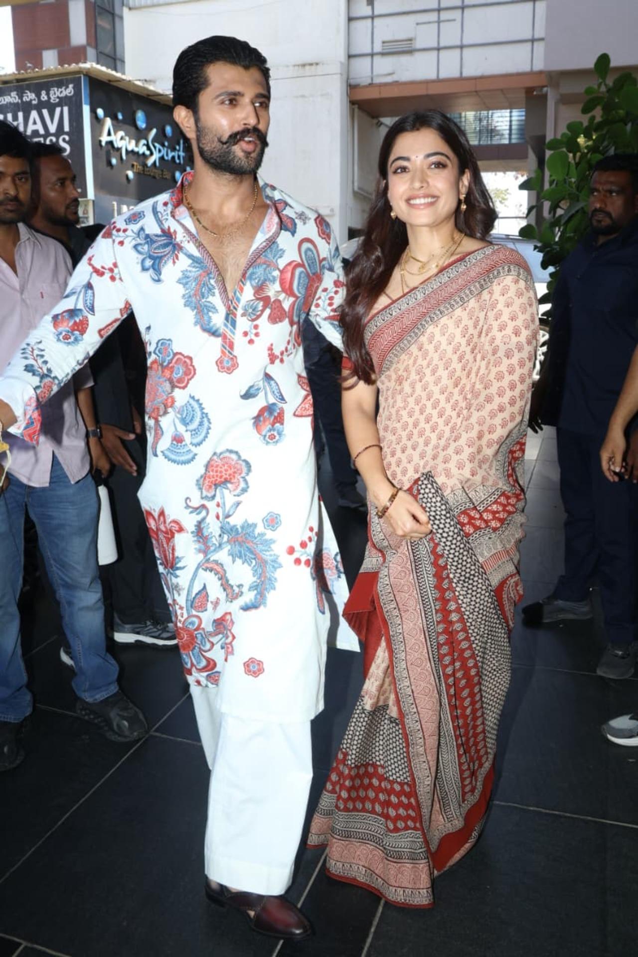 For the fan meet, Rashmika wore a sophisticated beige printed saree accented by a bold red border. She styled her hair in soft, cascading curls and layered several gold chains with her mangalsutra.